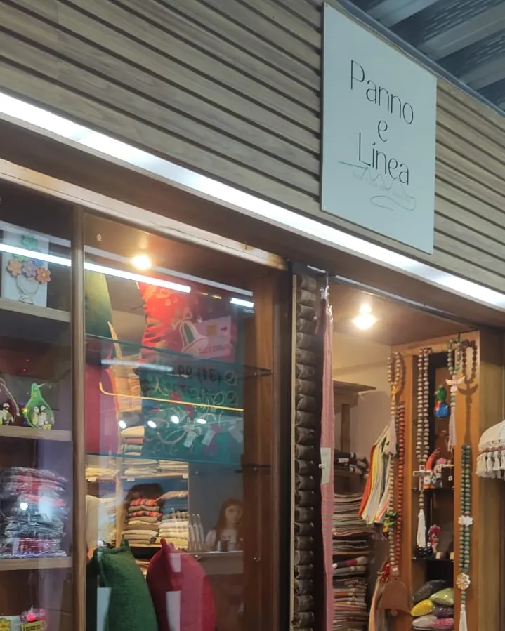 Fachada da Panno e Linea na Feira dos Produtores, com a placa da loja e almofadas na entrada