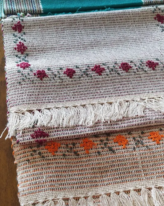 Tapetes de tear com franjas e desenhos bordados, empilhados